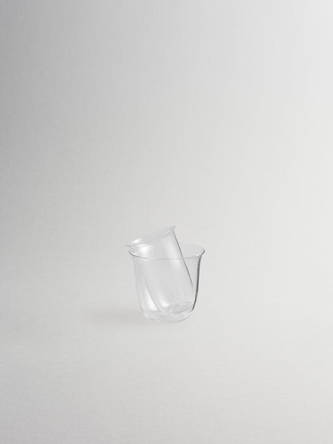 Small clear glass sidecar stacked inside clear glass ice bucket, shown on grey background.