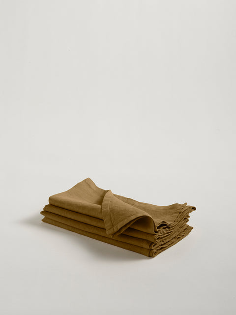 A stack of four folded olive green linen napkins, on grey background.