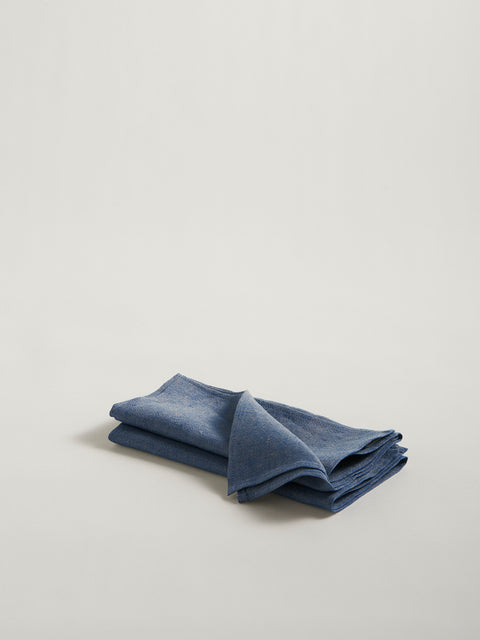 A stack of two folded indigo blue linen napkins, on grey background.