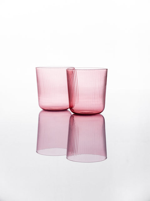 Two rose pink glass tumblers on a white background
