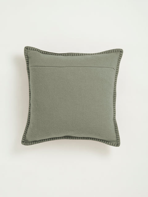 A square sage green throw pillow with dark green stitching around the edges, shown against a light gray background.